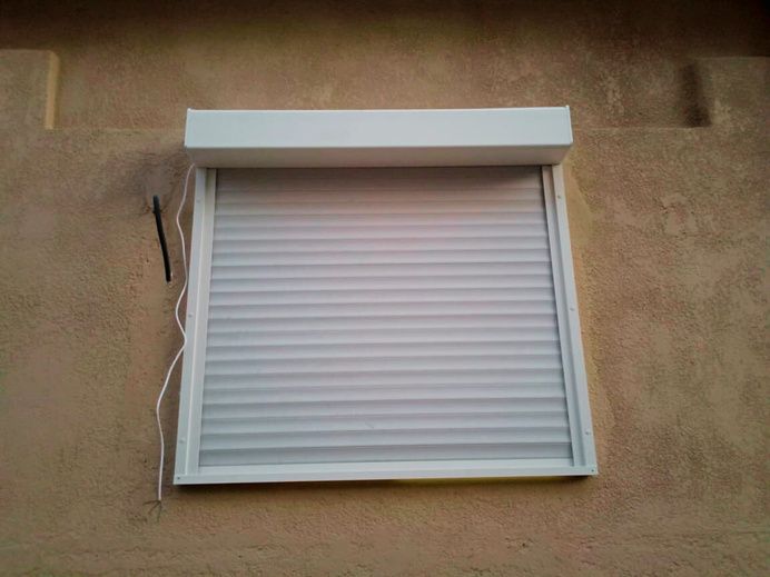 Volet roulant blanc sur une fenêtre en façade